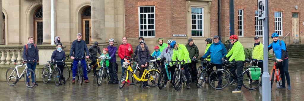 Photo of 20 people standing with bicycles outside a council building.